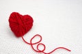 Red yarn ball like a heart on the white crochet background. Romantic Valentines Day concept. Red heart made of wool yarn with plac