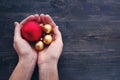 Red and yelllow round christmas balls in male hands on rustic wooden background.