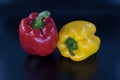 Red and yellow bell peppers isolated on black background, close up.