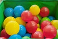 Red, yellow, blue plastic balls lie in the green box. The interior of the children`s room with lots of colorful toys.