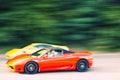 Red and yellow car driving fast on country road Royalty Free Stock Photo