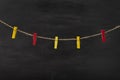Red and yellow clothespins on rope on black background. Space for text, mock up Royalty Free Stock Photo