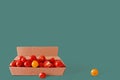 Red and yellow fresh cherry tomatoes in a cardboard box on a green background. Organic food concept. Creative image. Royalty Free Stock Photo