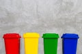 Red, Yellow, Green and Blue Recycle Bins. Concrete wall background.