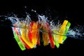 Red yellow and green pepper slices fall into water, on black background Royalty Free Stock Photo