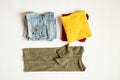 Red, yellow and green t-shirts and short denim shorts lie on a white background, laying out summer clothes Royalty Free Stock Photo