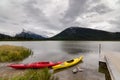 Red and yellow kayaks sitting by a dock with a view of Mount Rundle