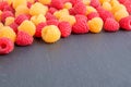 Red and yellow ripe natural fresh raspberries on black stone Royalty Free Stock Photo