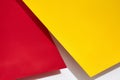 Red and yellow shadow-casting sheets of paper or stands above white surface. Advertising, branding area. Close up, copy