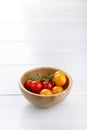 Red and yellow small cherry tomatoes in wooden bowl on white table Royalty Free Stock Photo