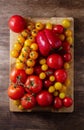 Red and yellow tomatoes, peppers on a wooden board, top view