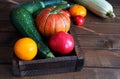 Red and yellow tomatoes, pumpkin and zucchini in a wooden box on the table. Autumn harvest. Royalty Free Stock Photo