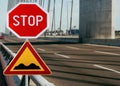 Red and yellow triangular warning road sign with STOP sign a warning of a bumpy road ahead