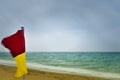 Red and yellow warning flag on a stormy beach Royalty Free Stock Photo