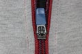 Red zipper fastener on grey shirt, close-up, macro shot.