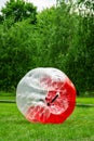 Red Zorbing Balloon on the summer lawn. Inflatable zorb ball outdoor. Leisure activity concept with vertical copy space Royalty Free Stock Photo