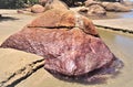 A reddish-colored stone at the edge of the freshwater stream Royalty Free Stock Photo