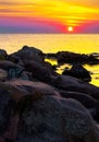 Reddish sunrise over the sea with rocky shore