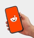 Reddit Editorial News background with symbolic face on mobile screen in hand. Stock price of reddit company concept Royalty Free Stock Photo