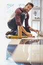 Redecorating from the floor up. Portrait of a smiling man laying floor tiles. Royalty Free Stock Photo