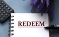 REDEEM - word are written on a notepad with a marker, calculator and lavender sprigs