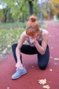 Redhaed woman in sportswear with painful ankle injury on running track Royalty Free Stock Photo