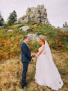 Redhair bride with happy groom holding hands on background of forest and Carpathian mountains. Royalty Free Stock Photo