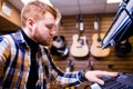 redhair ginger beard man is playing on piano in music store