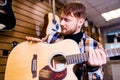 redhair ginger man is choosing quality acoustic guitar in guitar shop