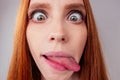 Redhair ginger woman demonstrating tongue and making stupid face with crossed eyes