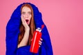 Redhair ginger woman holding red thermos and wrapped in in sleeping bag