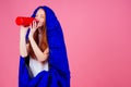 Redhair ginger woman holding red thermos and wrapped in in sleeping bag