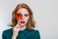 Redhaired beautiful girl in a green shirt with multi-colored round candy candy closes Dean`s eyes close-up