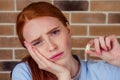 Redhaired ginger female with pain grimace holding white wisdom tooth after surgery removal extracted of a tooth