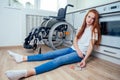 Redhaired ginger woman falling down and crawling for help in kitchen room ,holding pills in hands Royalty Free Stock Photo