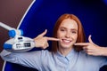 Redhaired ginger young cheerful female client sitting in dental office and getting smile whitening in egg chair Royalty Free Stock Photo