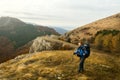 Redhead bearded hiker going up the trail path enjoying landscape. Backpacker man climbing a mountans with trekking poles