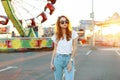 Redhead beautiful cute young hipster woman in stylish T-shirt in stylish jeans in trendy sunglasses is walking Royalty Free Stock Photo