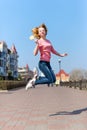 Redhead beautiful young woman jumping high in air over blue sky holding colorful lollipop. Pretty girl having fun outdoors. Royalty Free Stock Photo