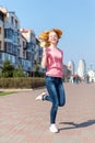 Redhead beautiful young woman jumping high in air over blue sky holding colorful lollipop. Pretty girl having fun outdoors. Royalty Free Stock Photo