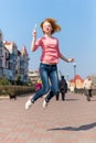 Redhead beautiful young woman jumping high in air over blue sky holding colorful lollipop. Pretty girl having fun outdoors. Royalty Free Stock Photo