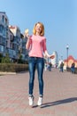 Redhead beautiful young woman jumping high in air over blue sky holding colorful lollipop. Pretty girl having fun outdoors. Royalty Free Stock Photo