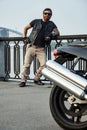 Redhead biker with beard in leather jacket leaning on railings n