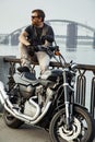 Redhead biker with beard in leather jacket sitting on railings n