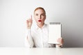 Redhead business woman posing in shirt holding empty notepad over white background. Royalty Free Stock Photo