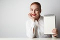 Redhead business woman posing in shirt holding empty notepad over white background. Royalty Free Stock Photo