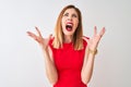 Redhead businesswoman wearing elegant red dress standing over isolated white background crazy and mad shouting and yelling with