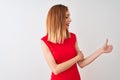 Redhead businesswoman wearing elegant red dress standing over isolated white background Looking proud, smiling doing thumbs up Royalty Free Stock Photo