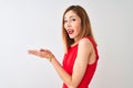 Redhead businesswoman wearing elegant red dress standing over isolated white background pointing aside with hands open palms Royalty Free Stock Photo