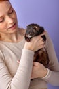 redhead lady posing with ferret isolated in studio on purple background, cute domestic animal Royalty Free Stock Photo